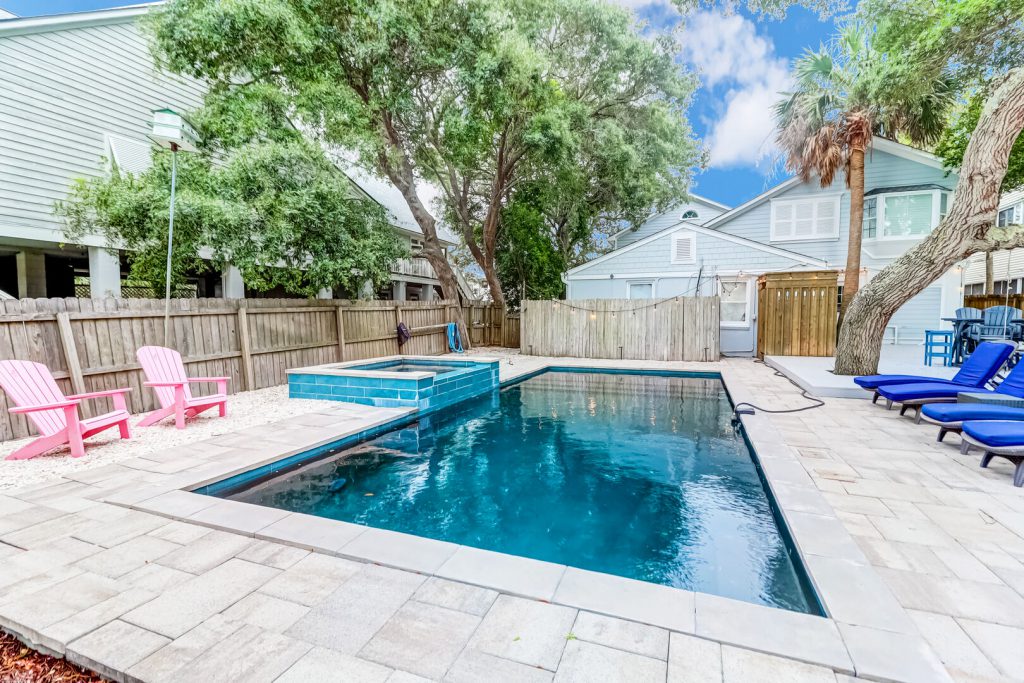 Heated Pool with Hot Tub at Vacation Rental on Isle of Palms, SC with pink chairs, stone pool deck, wooden fence