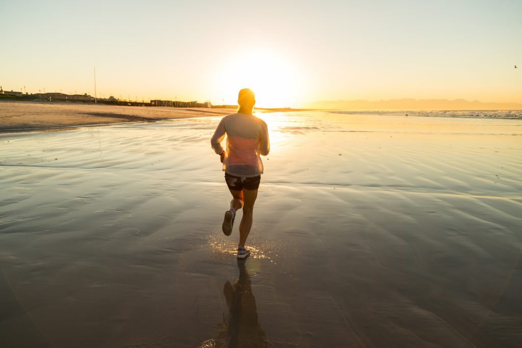 Young woman jogging along a beautiful deserted beach at dawn