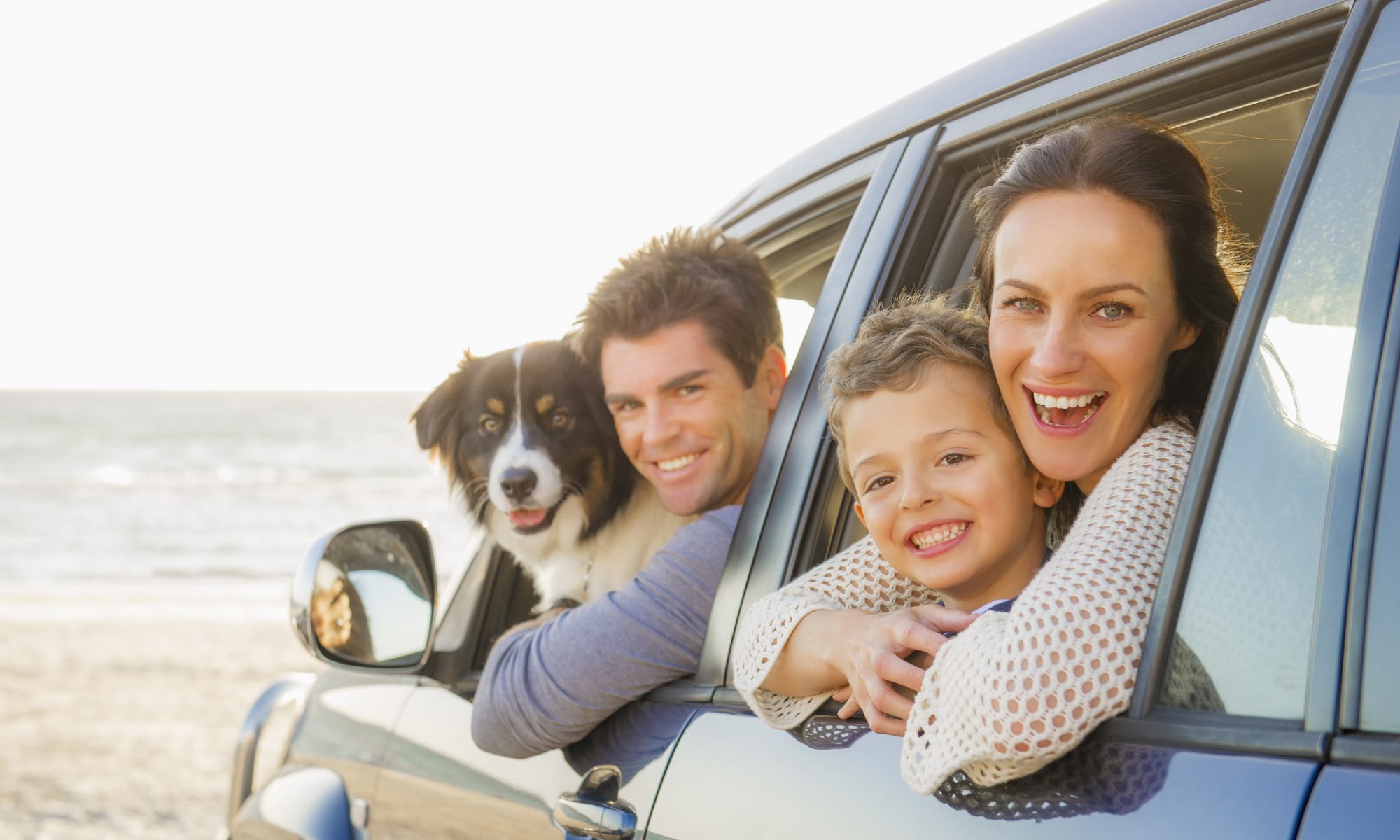 Caucasian family in car windows on beach