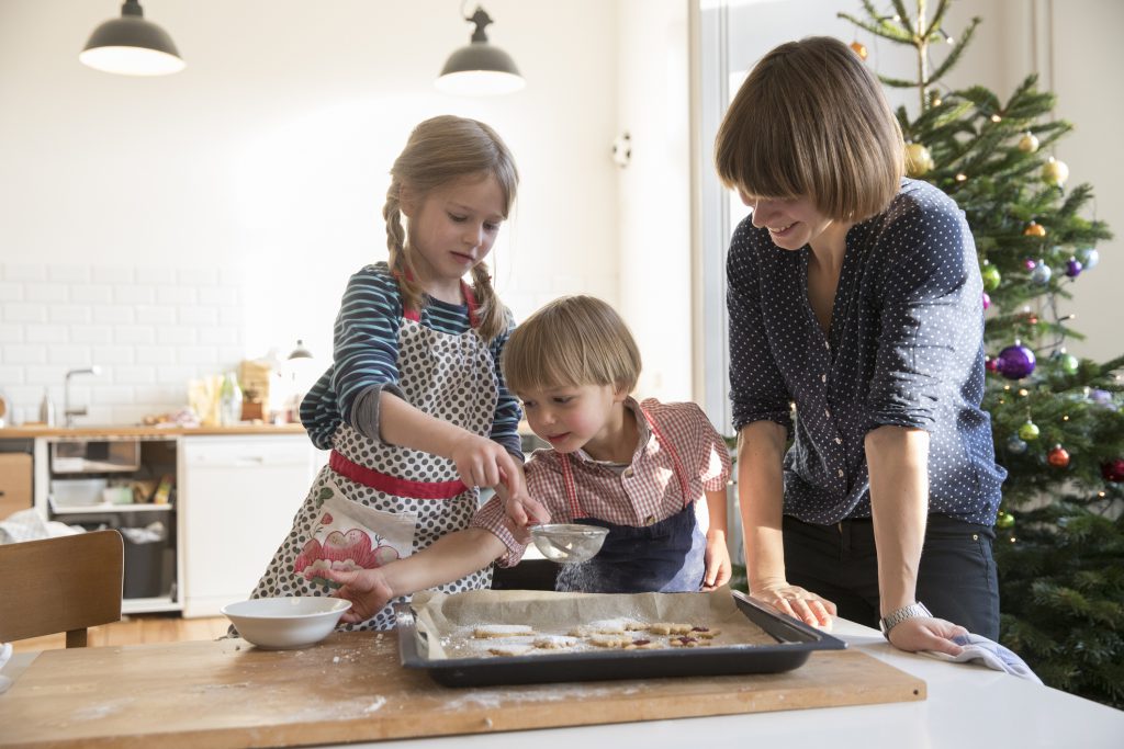 mother preparing cookies with toddler girl and boy at table in the kitchen