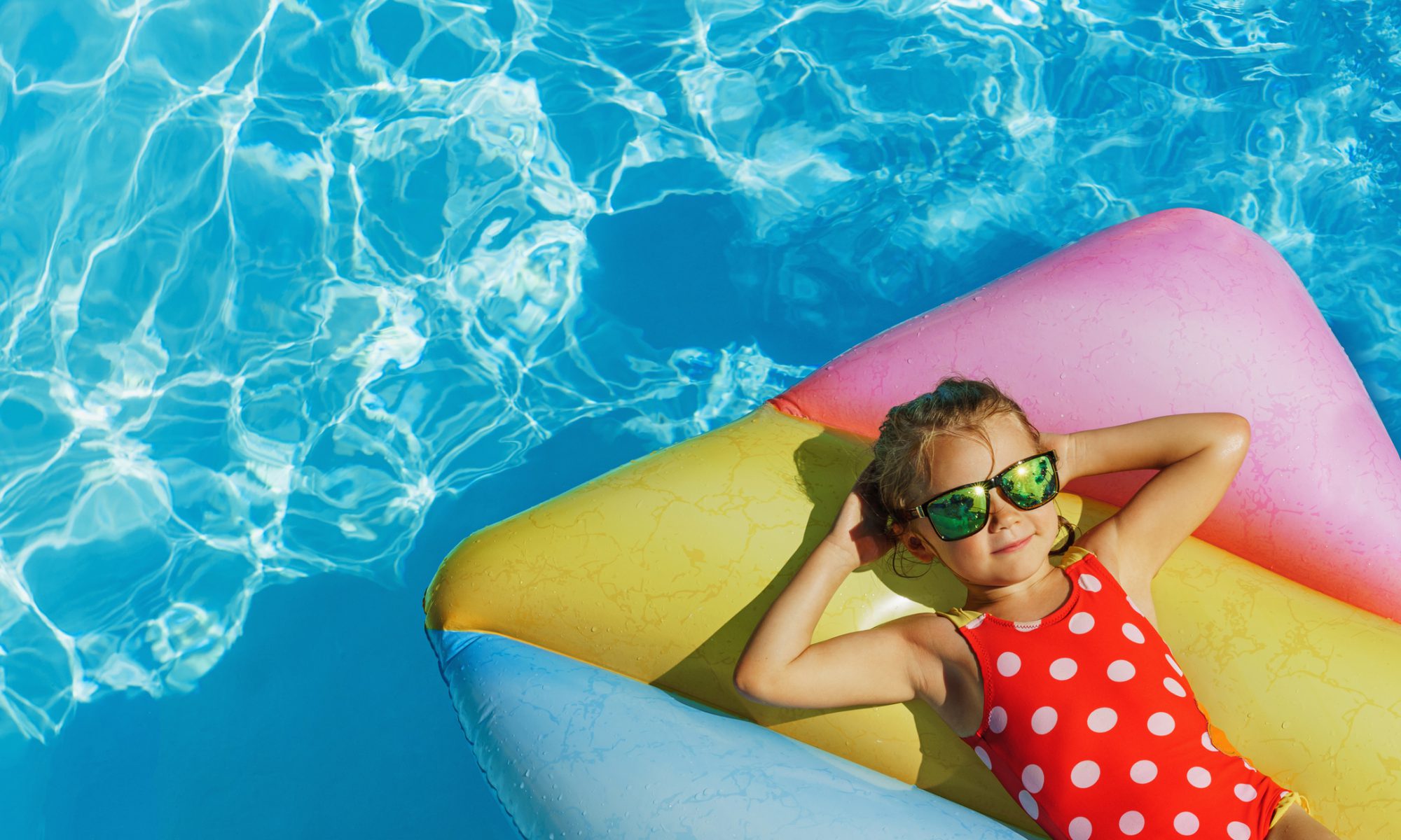 Child in swimming pool. Having fun on vacation at the hotel pool. Colorful vacation concept.